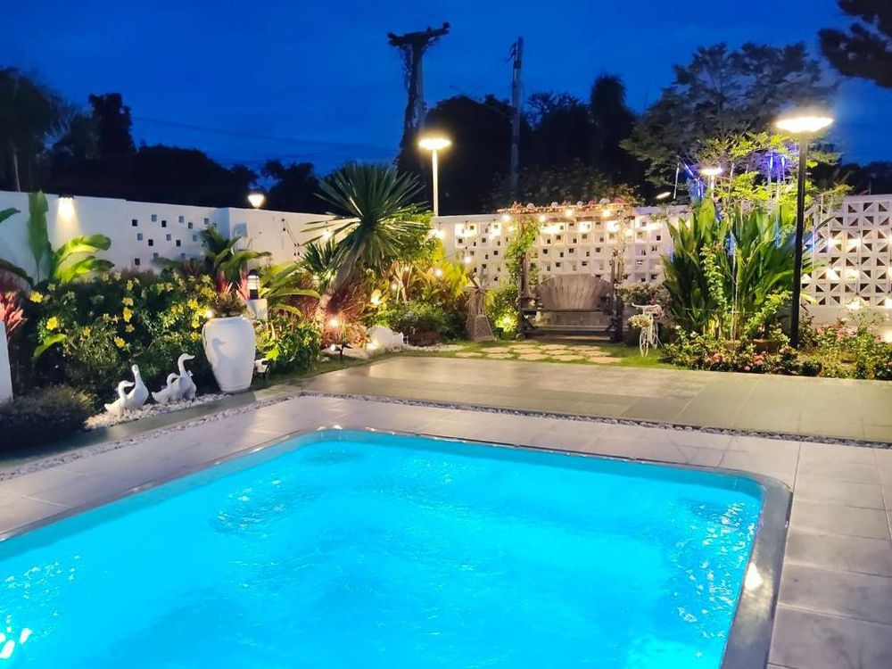 The pool lit blue at dusk, with garden lighting and planting